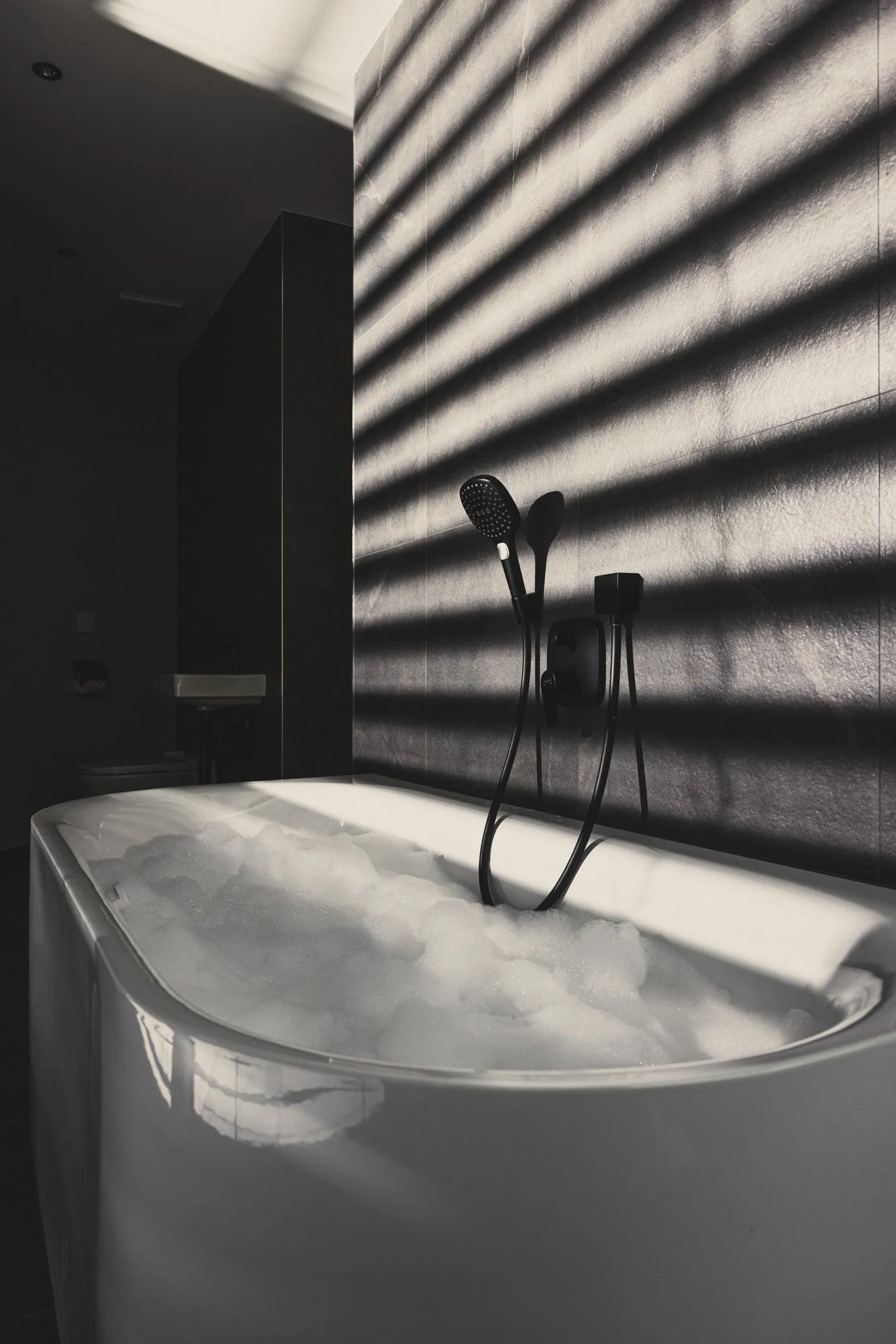Freistehende Badewanne mit Lichtstreifen an der dunklen Wand im DAS GERLOS