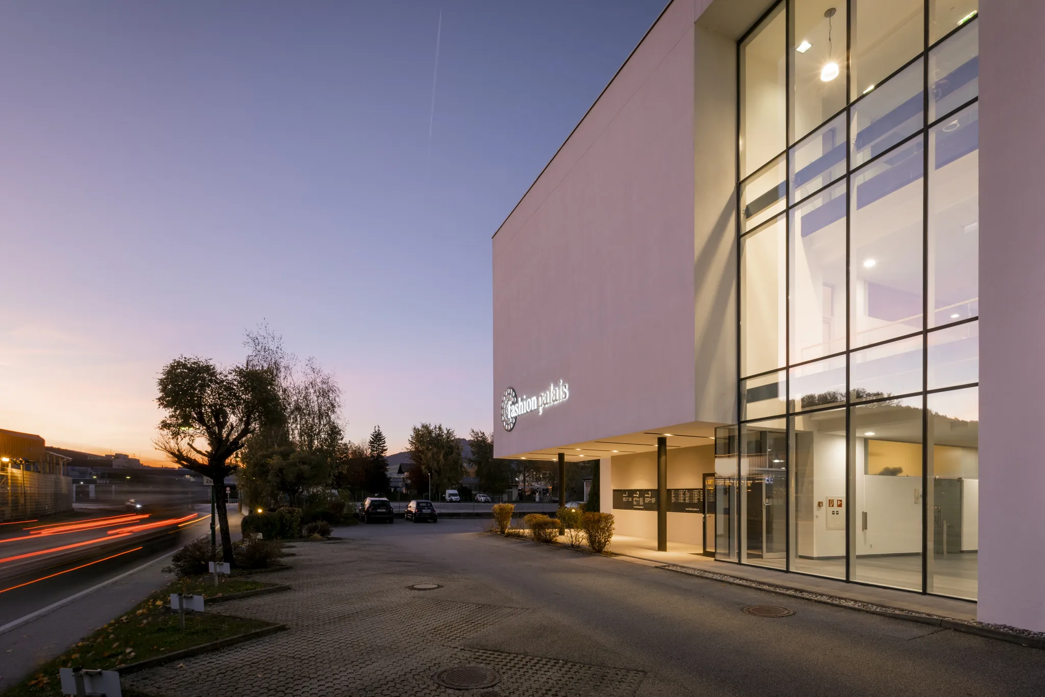 Beleuchteter Eingang des Fashionpalais zur blauen Stunde mit Lichtspuren