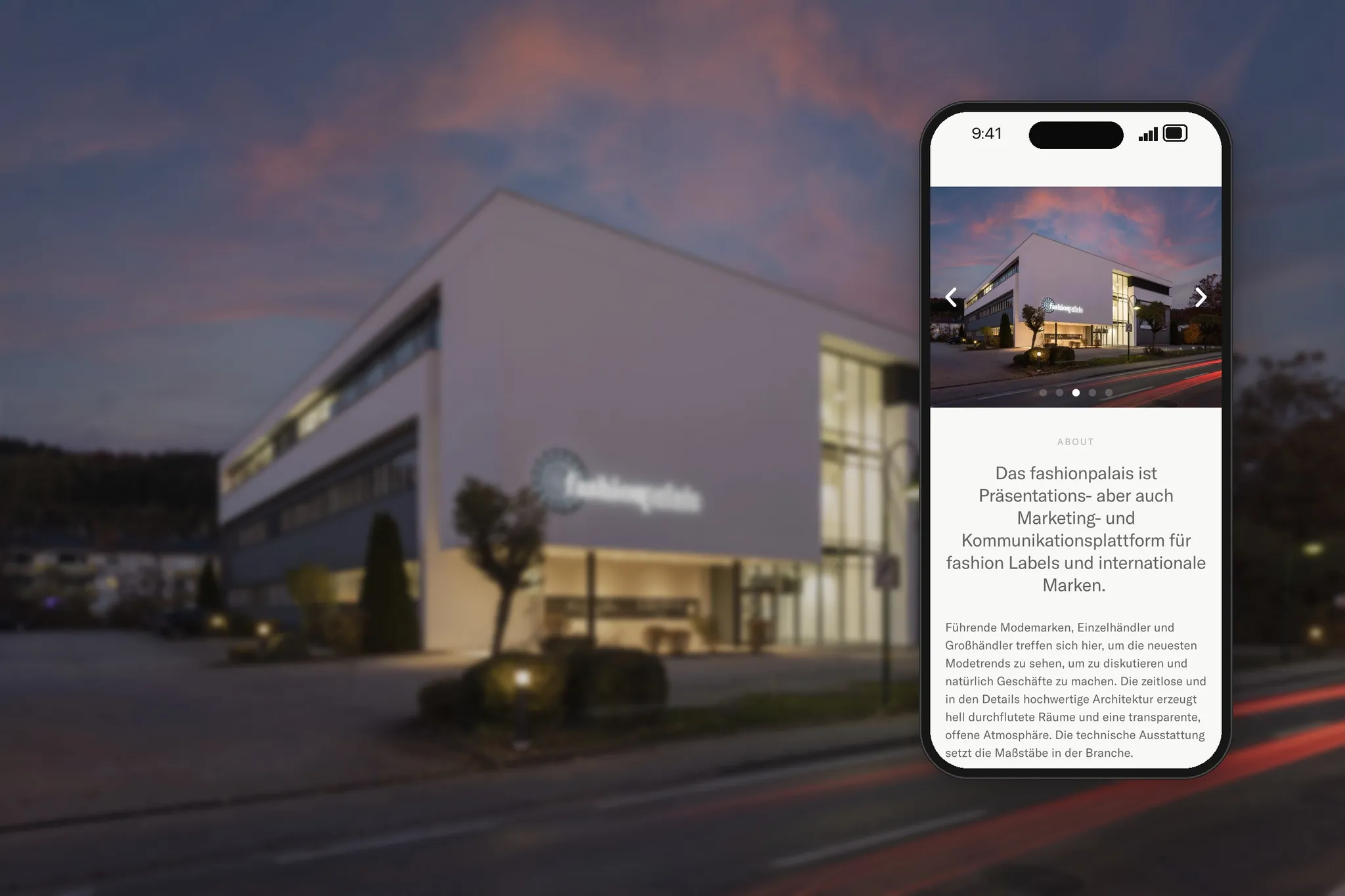 Smartphone mit der Website des Fashionpalais vor dem Gebäude in der Abenddämmerung