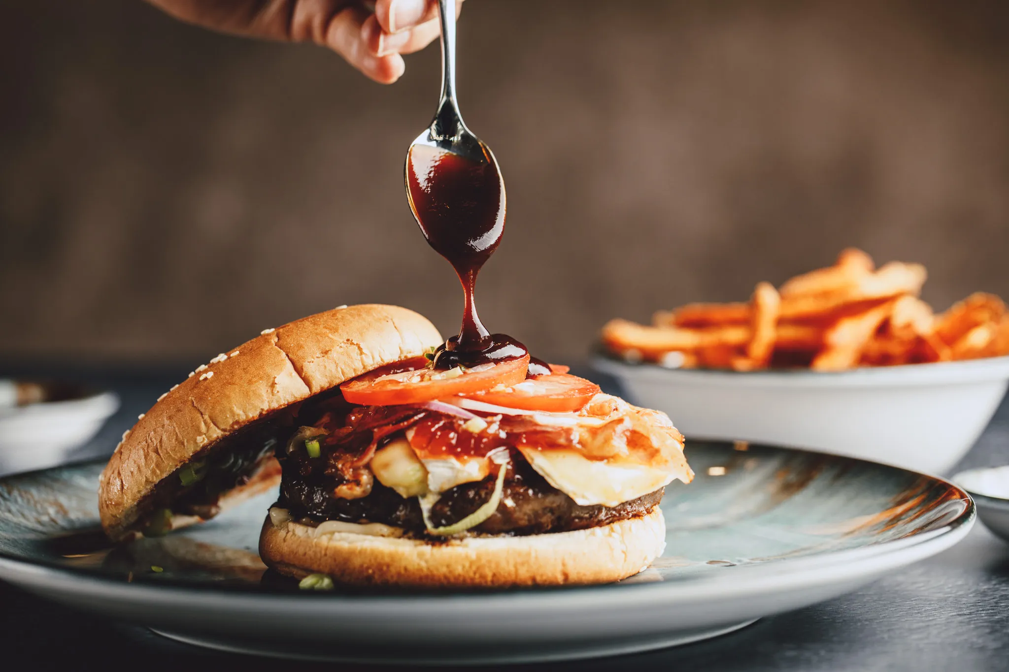 BBQ-Sauce tropft vom Löffel auf einen Burger, Das Brixx