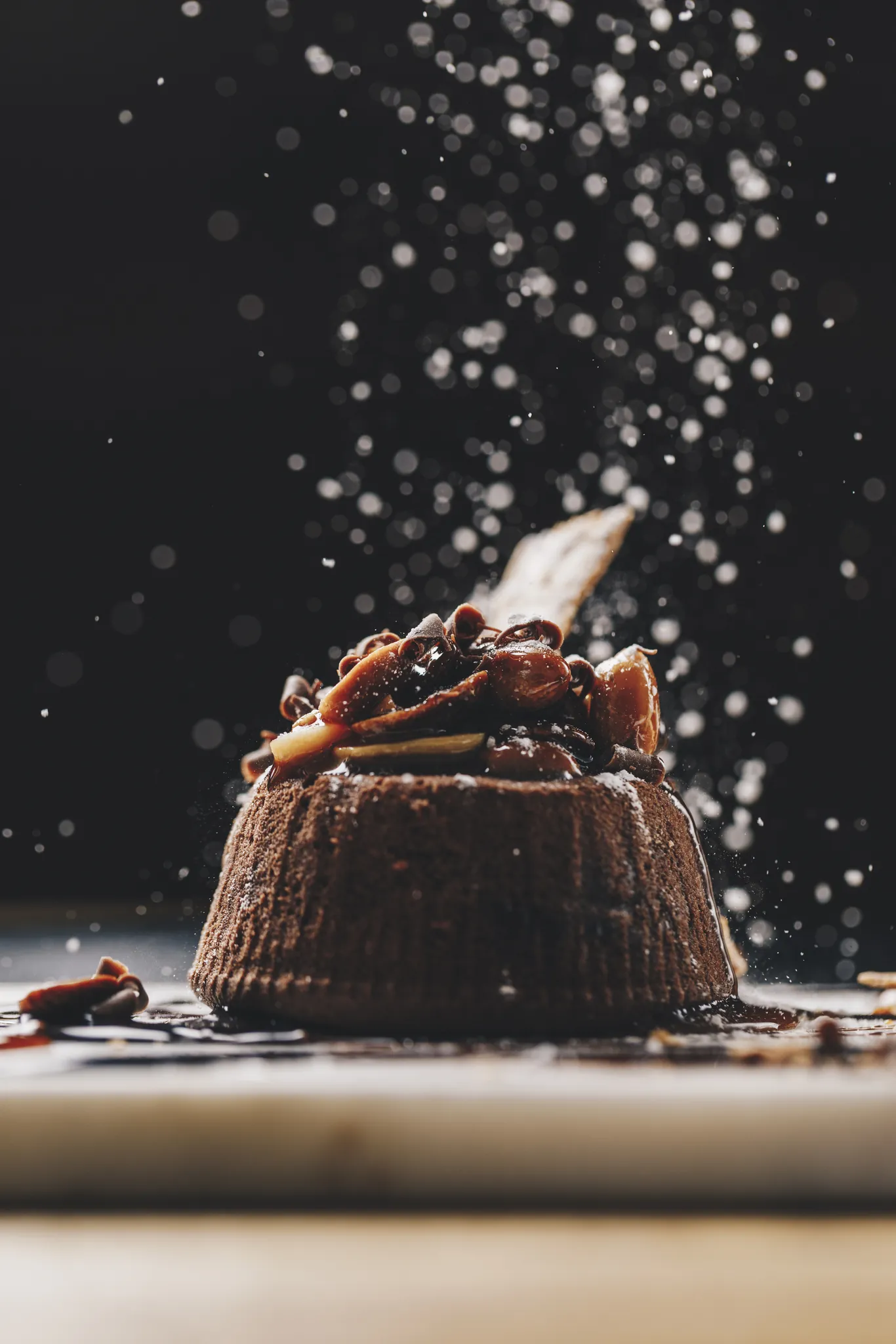 Schokoladendessert wird vor dunklem Hintergrund mit Puderzucker bestäubt, Woods Seefeld