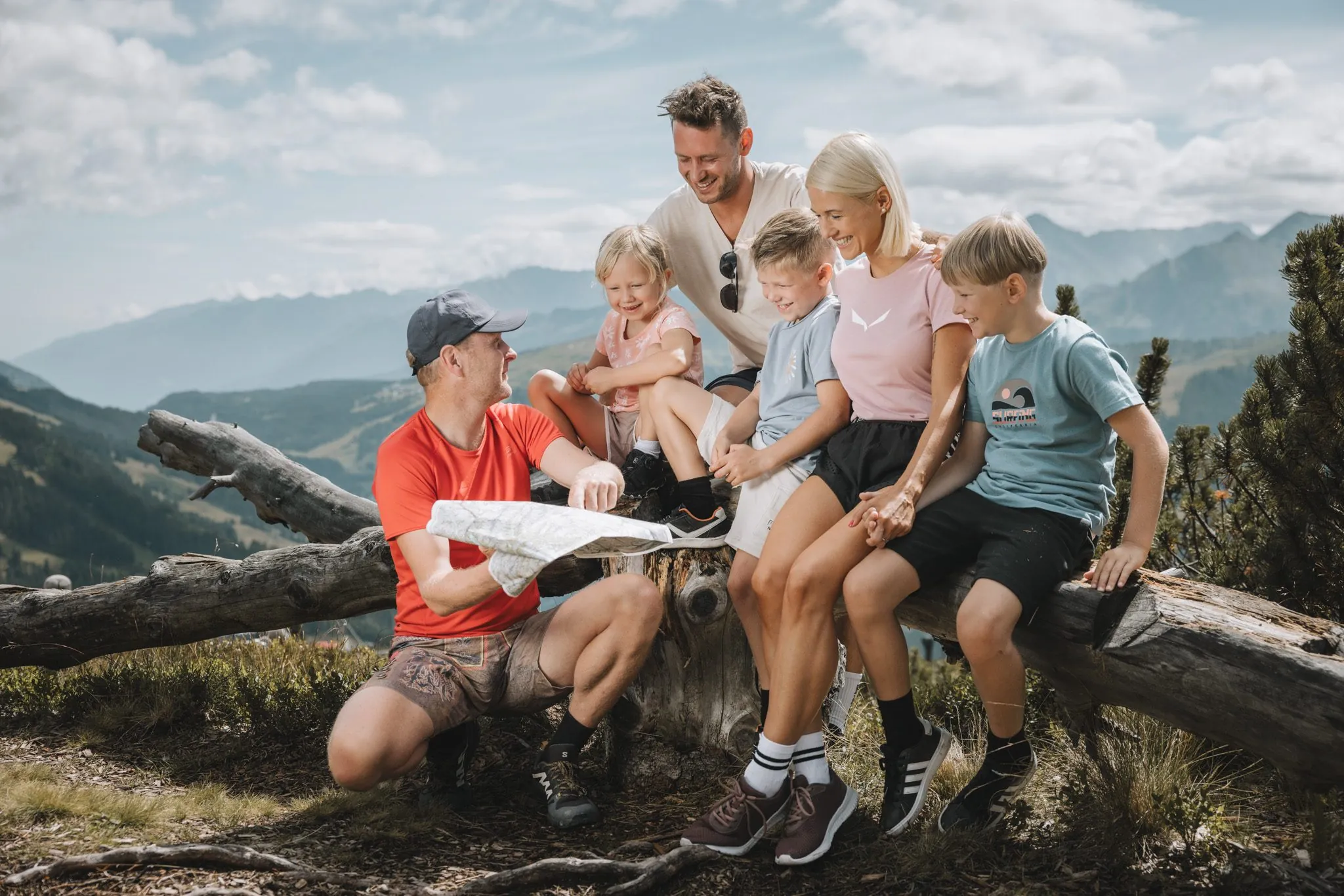 Familie sitzt gemeinsam auf einer Bank mit Wanderkarte, Gaspingerhof