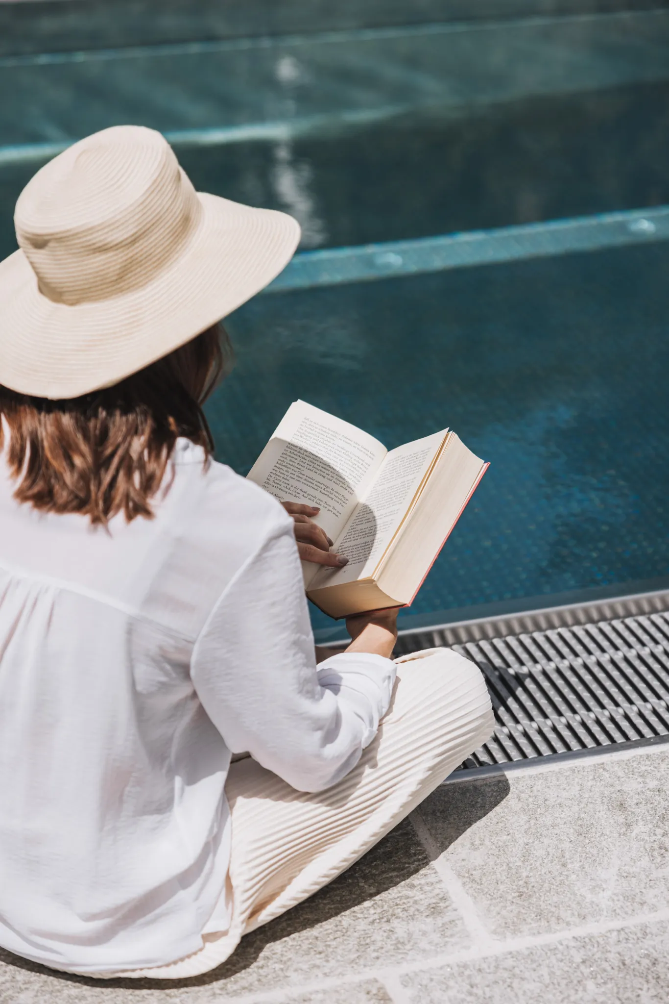 Gast liest mit Sonnenhut am Pool, Gaspingerhof