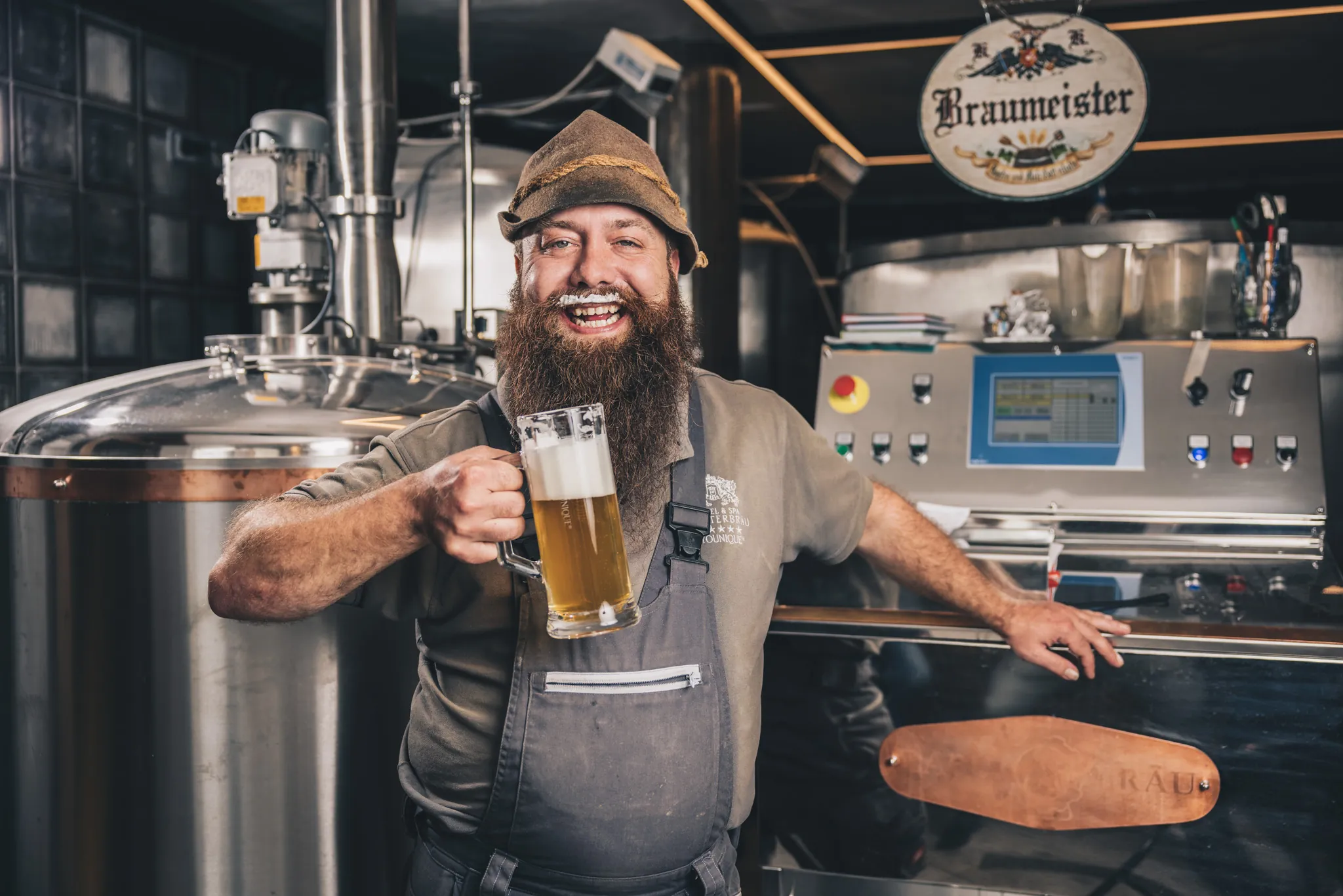 Lachender Braumeister mit Bierkrug in der Hausbrauerei des Hotel Klosterbräu