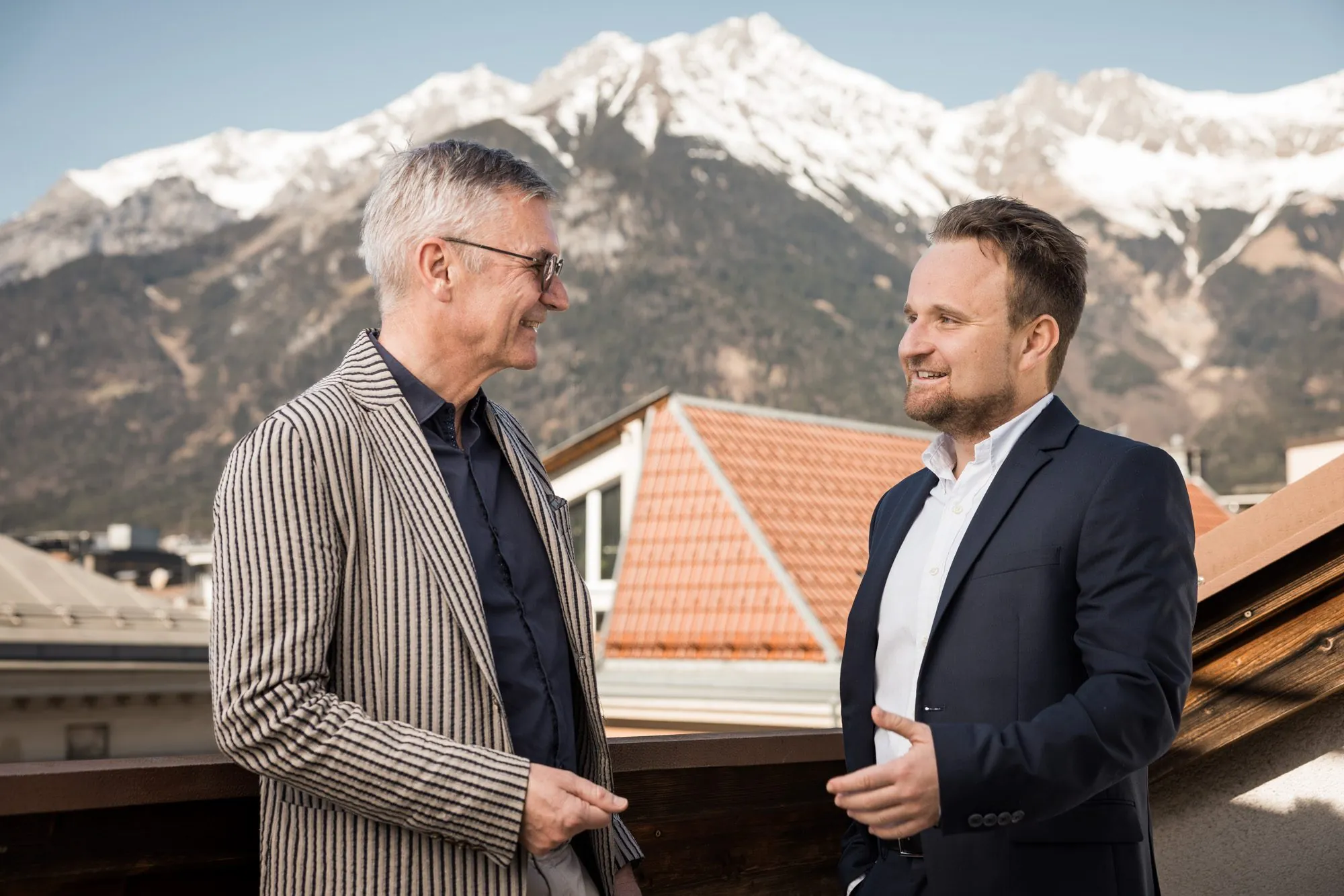 Zwei Partner im Gespräch auf der Dachterrasse, im Hintergrund die Nordkette