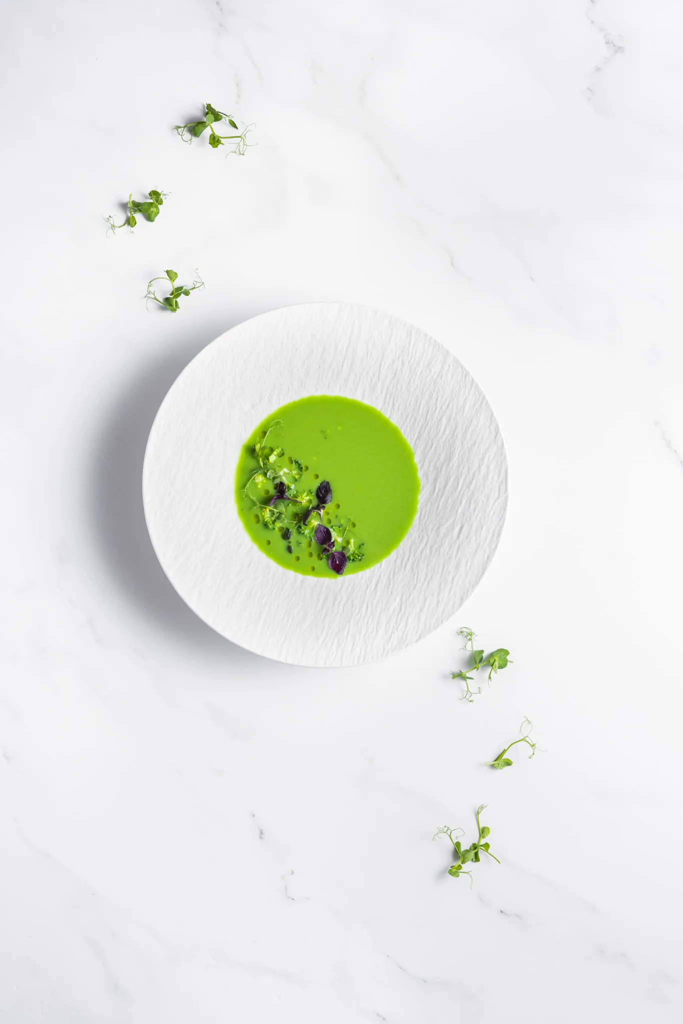 Grüne Erbsensuppe mit Kresse in tiefem Teller auf weißem Marmor, Park Igls