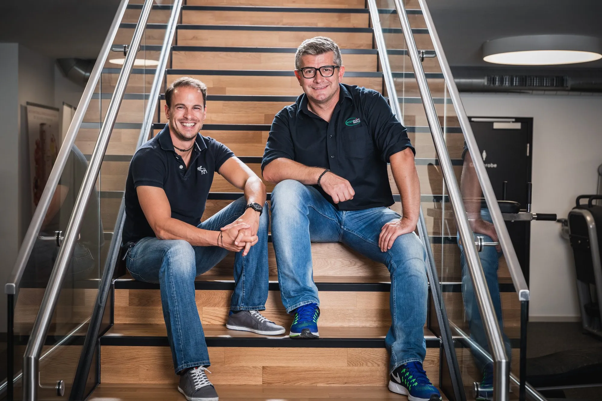 Zwei Inhaber sitzen auf der Treppe ihres Studios, Business Portrait