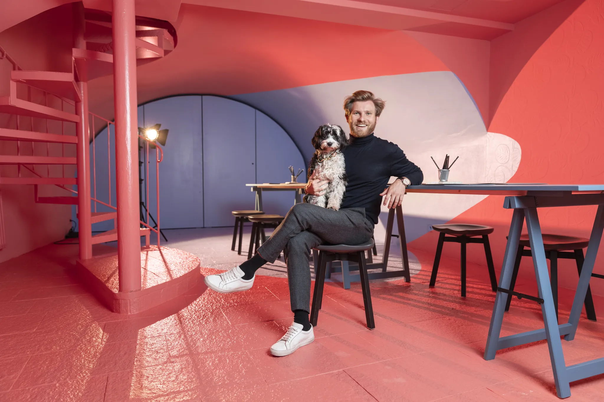Designer mit Hund am Arbeitstisch in farbigen Räumen, Business Portrait on Location
