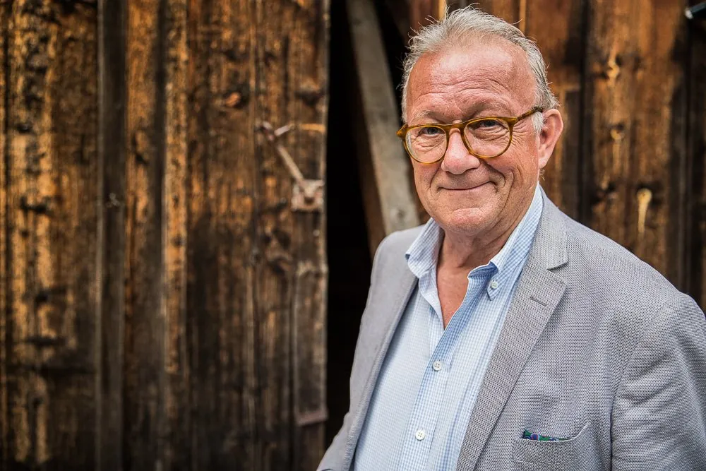 Portrait vor verwitterter Holzwand bei einer Vernissage