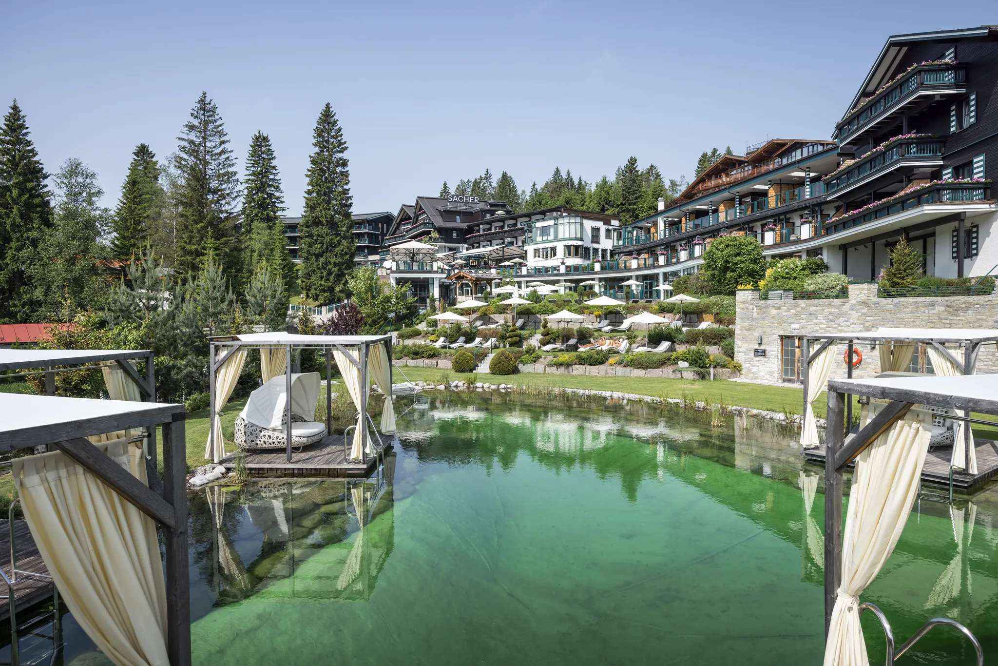 Außenanlage des Alpin Resort Sacher mit Pool und Bergblick