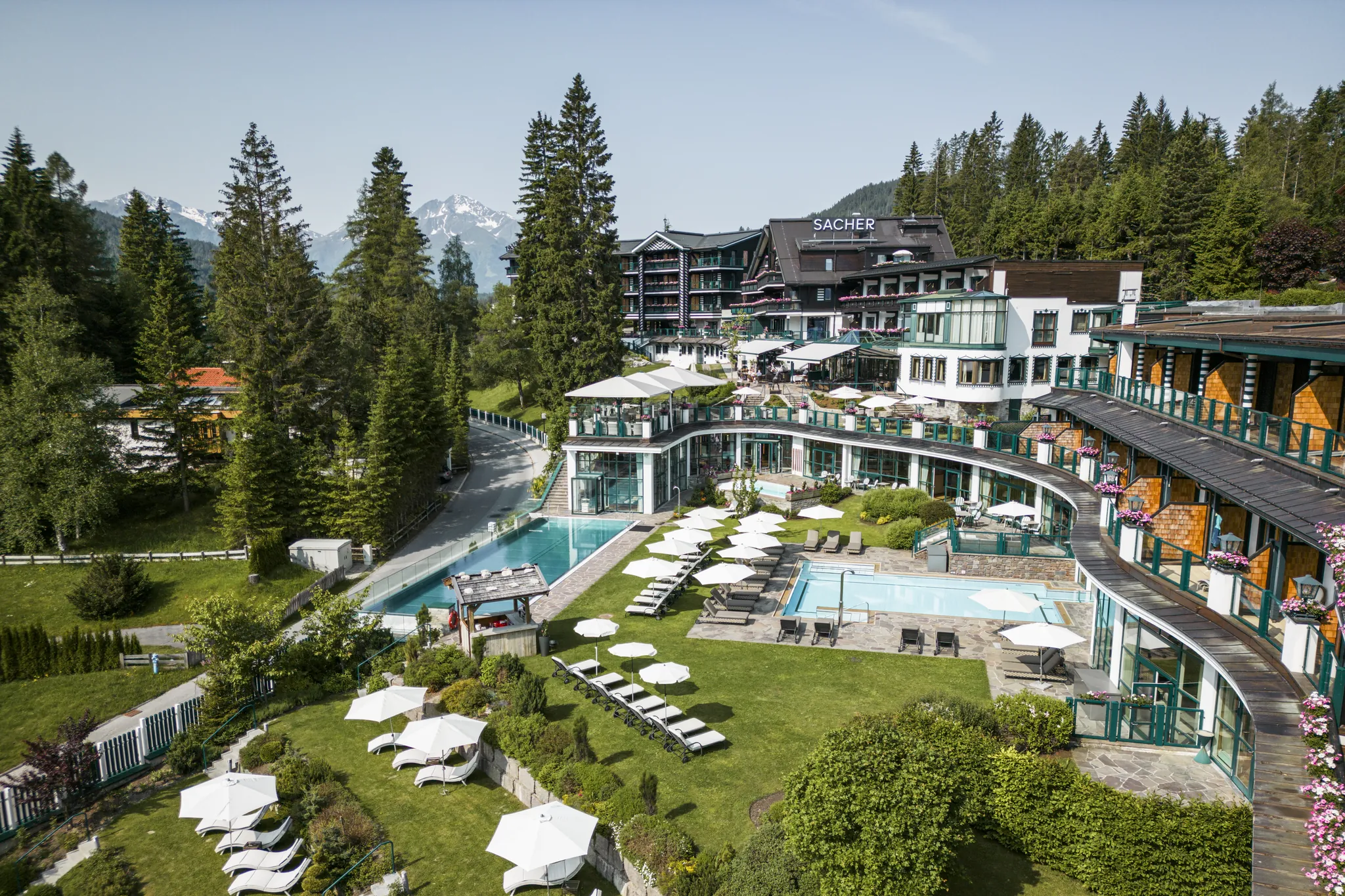 Drohnenaufnahme des Alpin Resort Sacher mit Pool und Liegewiese