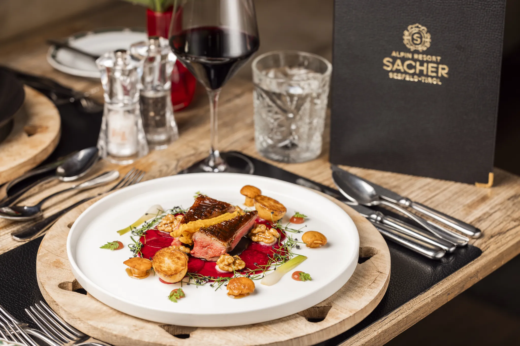 Gedeckter Tisch mit Hauptgang, Rotwein und Speisekarte, Alpin Resort Sacher