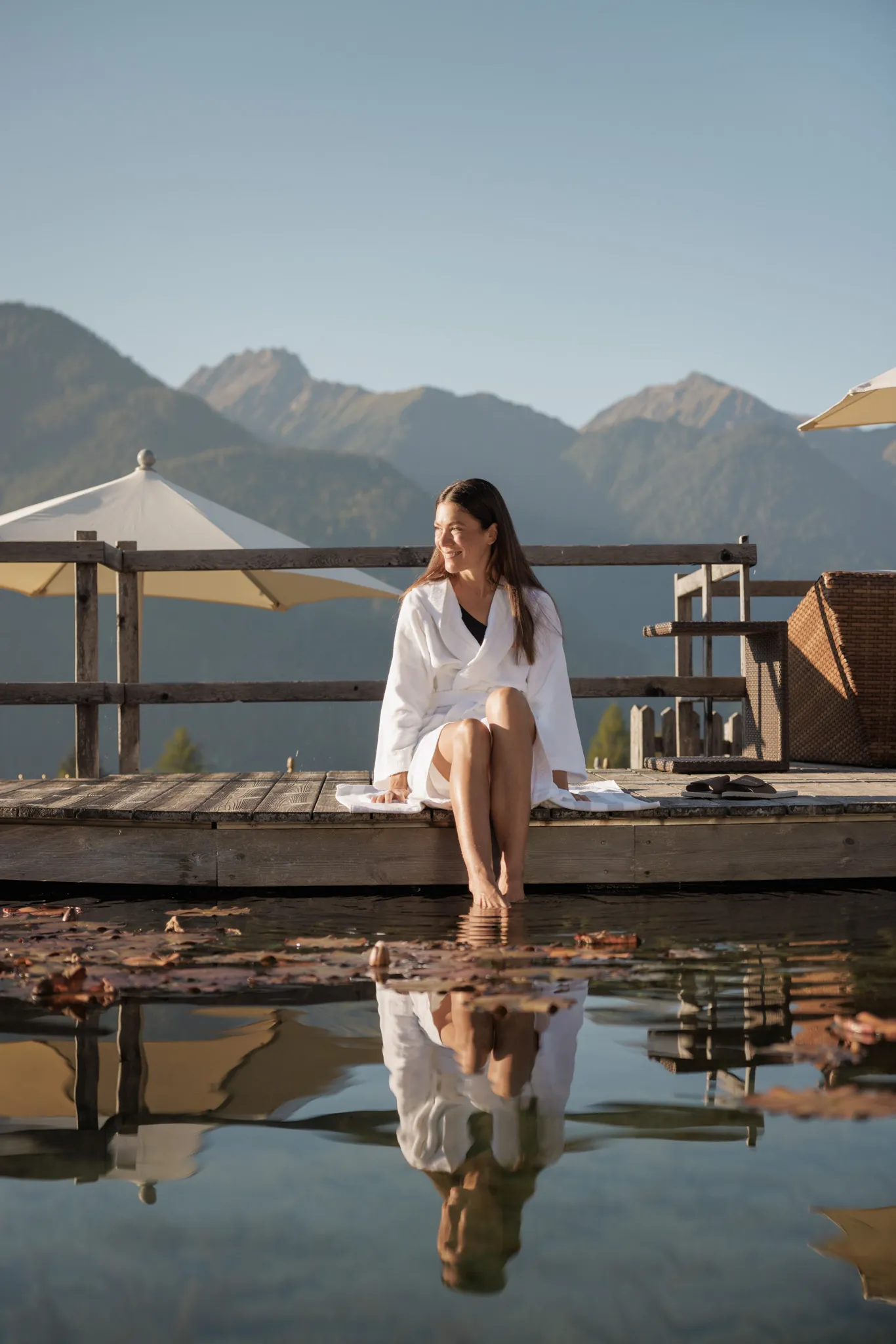 Frau im Bademantel am Steg des Naturteichs