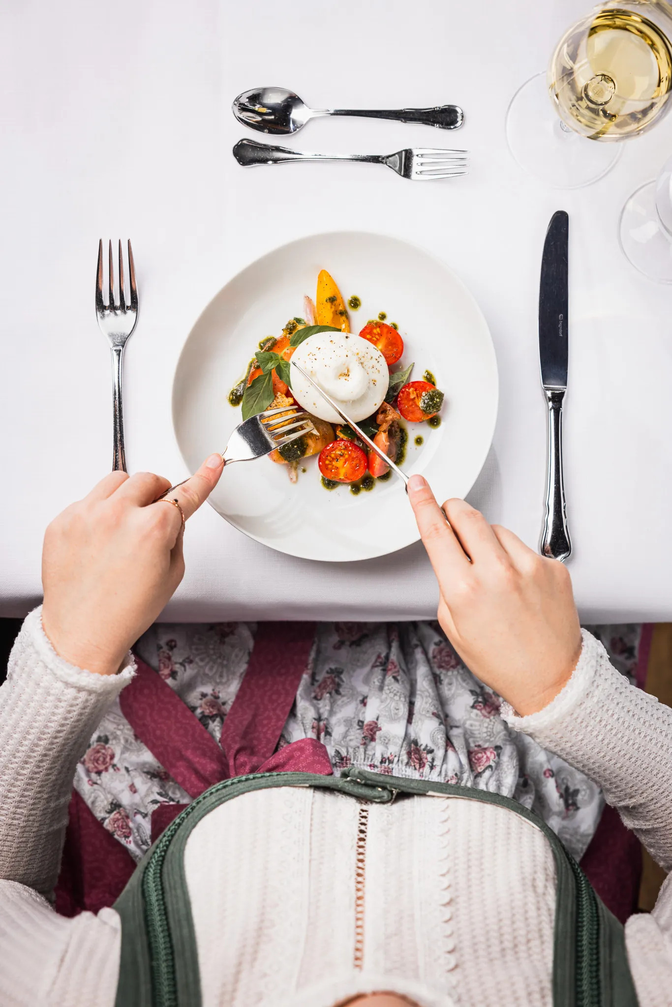 Gast in Tiroler Tracht genießt Burrata-Caprese-Salat